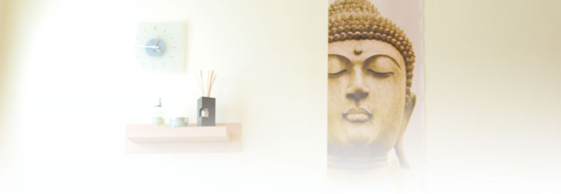 Ruhiger Empfangsbereich mit Buddha-Figur, Wanduhr und Duftöl